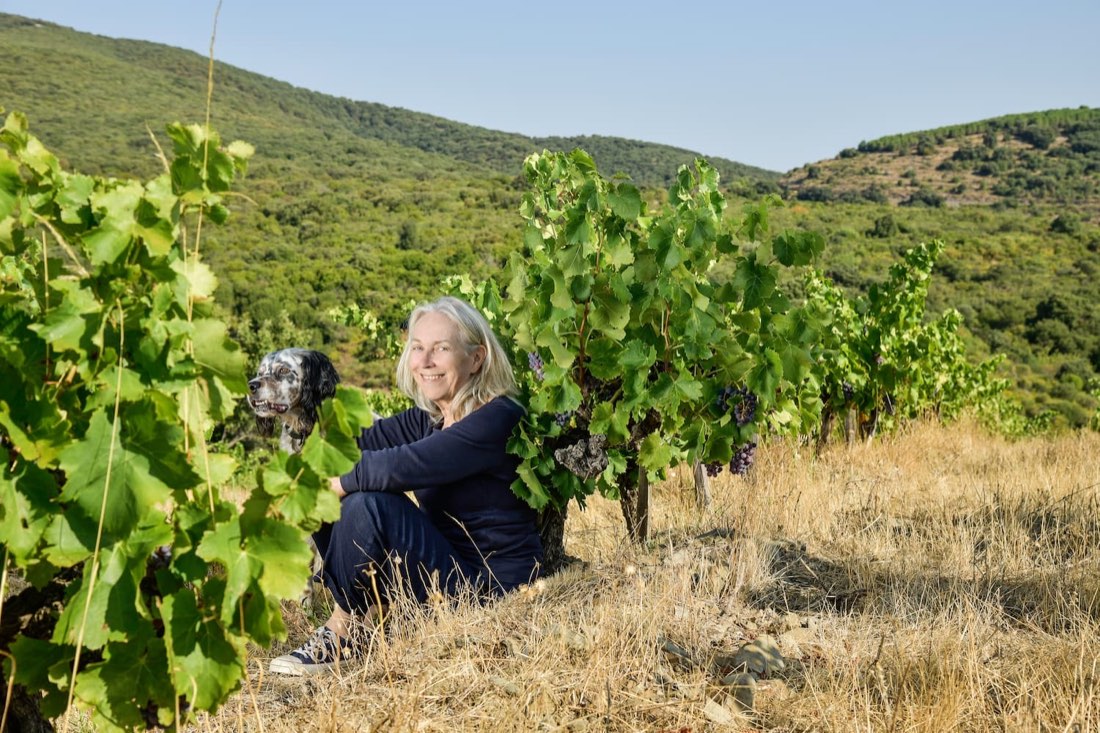 Brigitte Chevalier sitter bland vinrankorna med sin hund